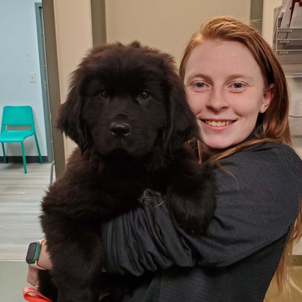 women holding a black fluffy dog